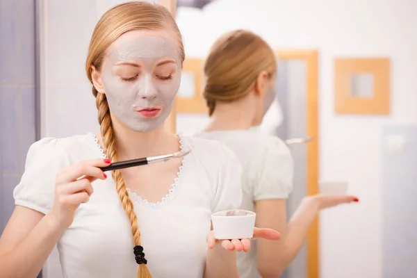 女性が彼女の顔にブラシ粘土泥マスクを適用します。 — ストック写真