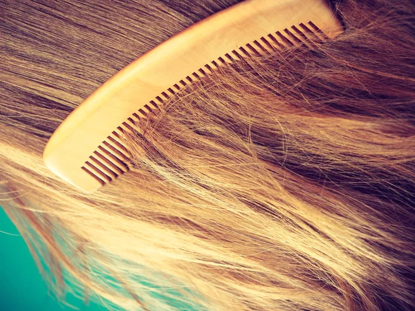 Straight brown hair with wooden comb closeup