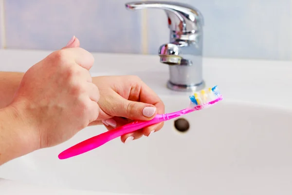 Mão segurando escova de dentes no banheiro — Fotografia de Stock