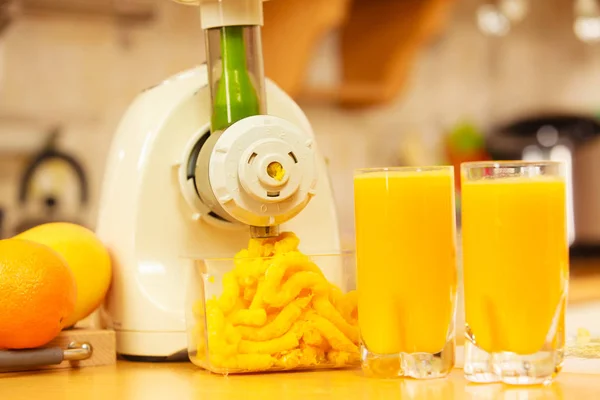 Making orange juice in juicer machine in kitchen — Stock Photo, Image