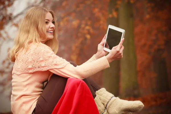 Женщина с цифровым планшетом в осеннем парке — стоковое фото