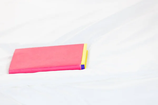 Calendario portátil rosa acostado en la cama blanca —  Fotos de Stock