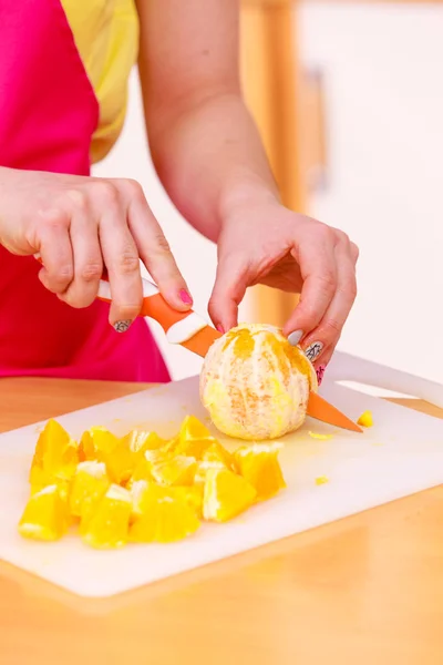 Mulher dona de casa na cozinha cortando frutas laranja — Fotografia de Stock