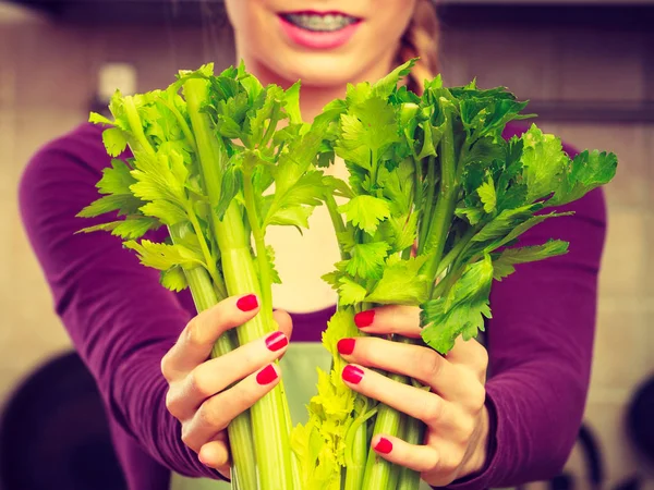 在厨房里的女人抱着绿色的芹菜 — 图库照片