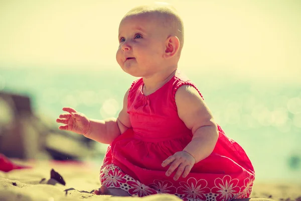 Kis baba ül és játszik a tengerparton — Stock Fotó