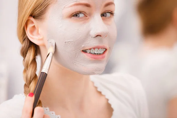 Gelukkig jonge vrouw modder masker aanbrengen op gezicht — Stockfoto