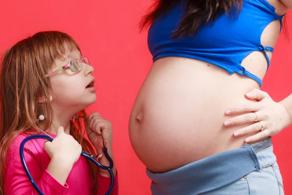 Fille utilisant le stéthoscope sur la mère enceinte — Photo
