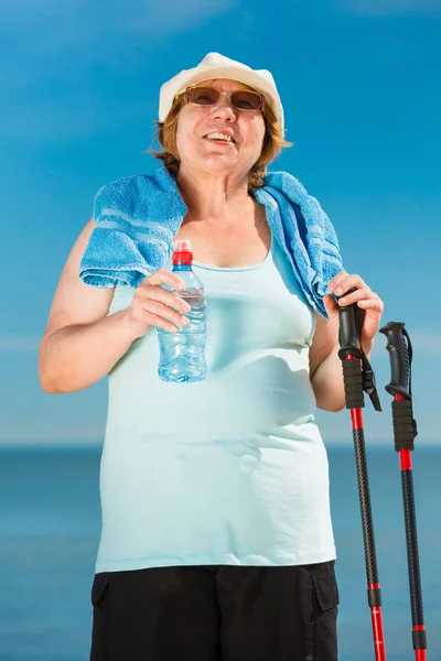 Senior woman practicing nordic walking on beach — Stock Photo, Image