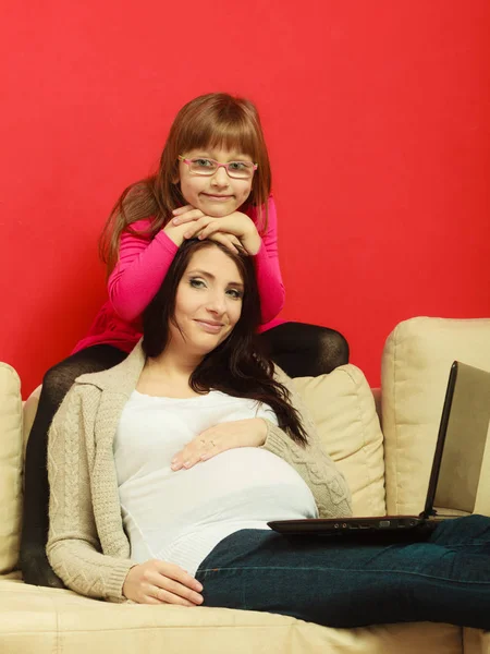 Pregnant woman and daughter sitting with laptop — Stock Photo, Image