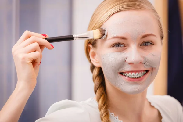 Vrouw met borstel klei modder masker toepassen op haar gezicht — Stockfoto