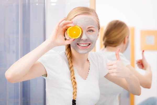 Jovem feliz tendo máscara facial segurando kiwi — Fotografia de Stock