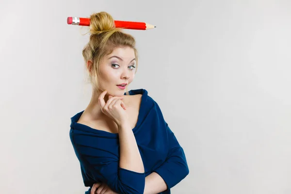 Tänkande blond kvinna med stora penna i hår — Stockfoto