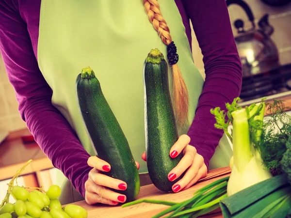 Mulher na cozinha detém abobrinha vegetal — Fotografia de Stock