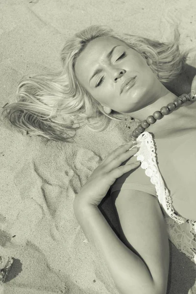 Woman lying on sandy beach relaxing during summer Stock Picture