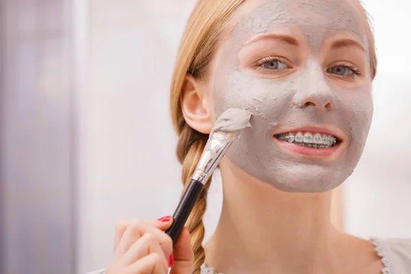 Wanita menerapkan dengan kuas lumpur masker ke wajahnya — Stok Foto