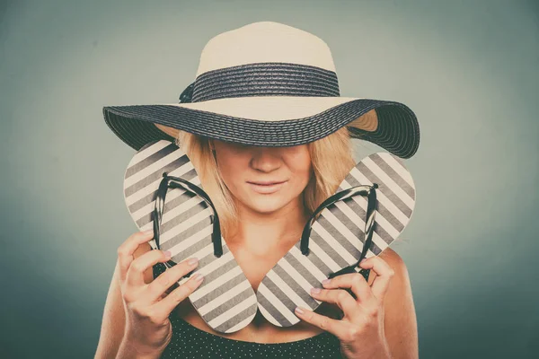 Женщина в солнечной шляпе, держит шлепанцы — стоковое фото