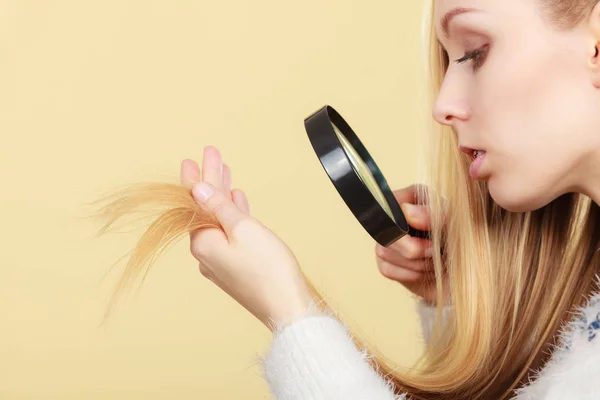 Donna triste guardando le estremità dei capelli danneggiati . — Foto Stock