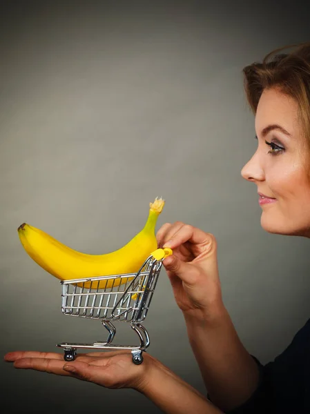 Mujer sosteniendo carrito de compras con plátano dentro — Foto de Stock