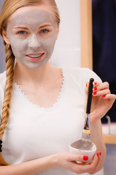 Mujer aplicando con la máscara de barro cepillo de barro en su cara — Foto de Stock