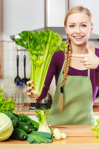 Femme dans la cuisine tient céleri vert — Photo