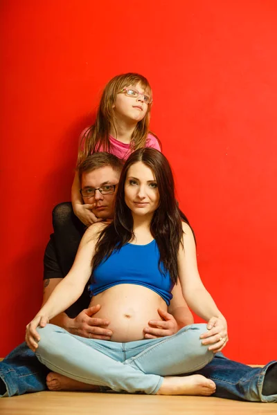 Mujer embarazada, hombre e hija posando . — Foto de Stock