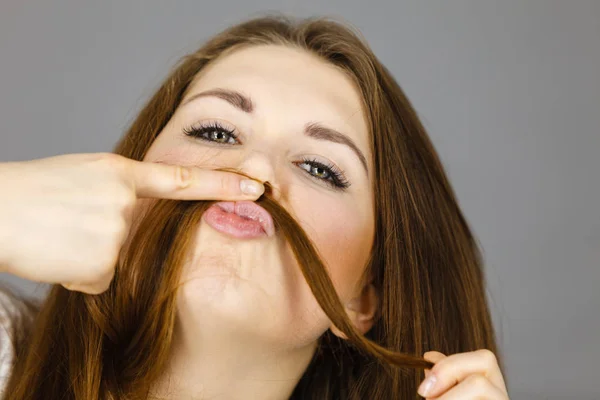 Mujer divirtiéndose con su pelo haciendo bigote — Foto de Stock