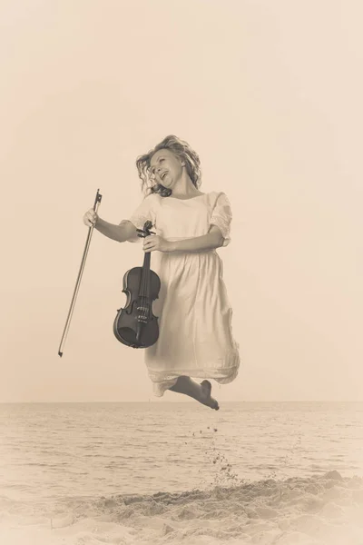 Žena na pláži u moře se držení houslí — Stock fotografie