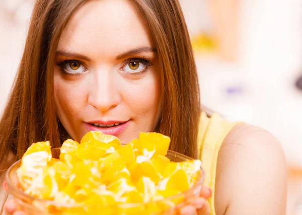 Woman holds bowl full of sliced orange fruits — Stock Photo, Image