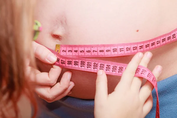 Daughter measuring pregnant woman belly with tape — Stock Photo, Image