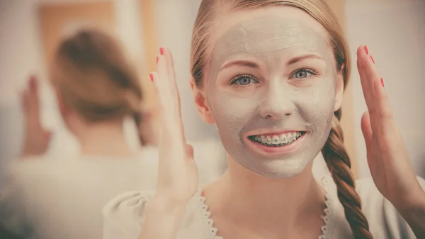 Vrouw met grijze klei modder masker op haar gezicht — Stockfoto