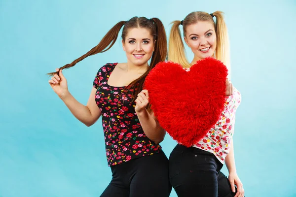 Felice due donne che tengono il cuscino a forma di cuore — Foto Stock