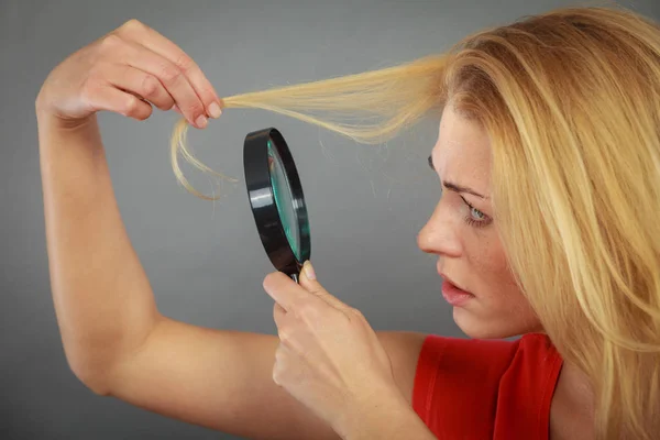 Femme regardant les cheveux à travers la loupe — Photo