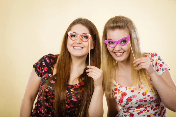 Twee gelukkige vrouwen houden van nep brillen op stick — Stockfoto