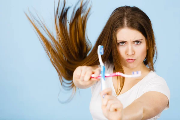 Mulher segurando duas escovas de dentes cruzadas — Fotografia de Stock