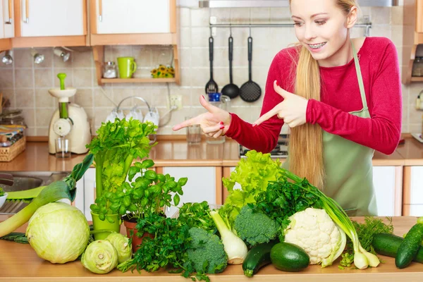 Mulher na cozinha com muitos vegetais verdes — Fotografia de Stock