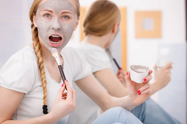 Gelukkig jonge vrouw modder masker aanbrengen op gezicht — Stockfoto