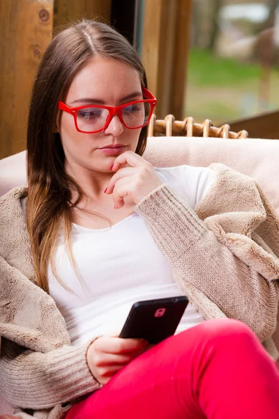 Vrouw zit op stoel met behulp van telefoon thuis — Stockfoto