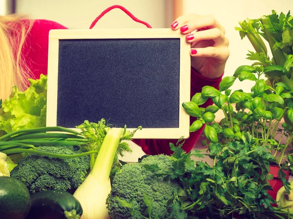 Mujer que tiene verduras verdes en la junta —  Fotos de Stock