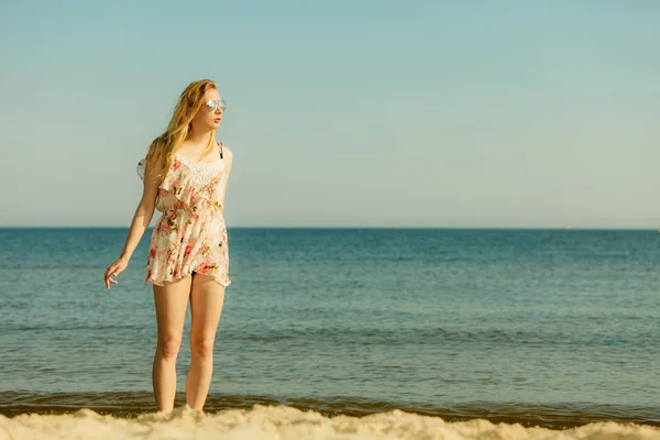 Frau im Sommerkleid spaziert am Strand — Stockfoto