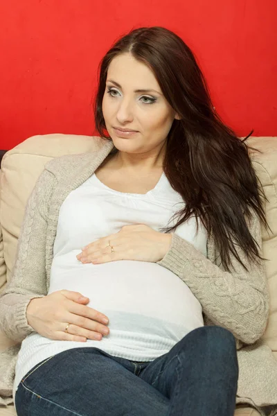Oturma ve kanepede rahatlatıcı hamile kadın — Stok fotoğraf