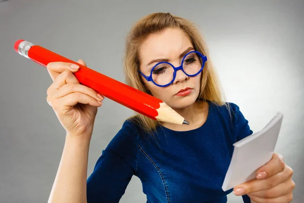 Ernsthafte Frau hält großes Bleistiftpapier in der Hand — Stockfoto