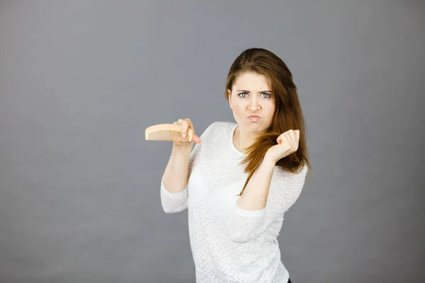 Angry woman trying to brush her hair — Stock Photo, Image