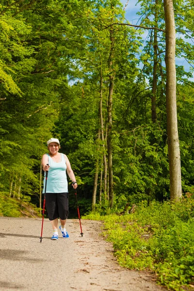 Senior woman practicing nordic walking in park — Stock Photo, Image