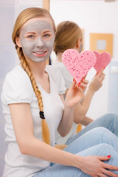 Kalp sünger tutan gri yüz maskesi olan kadın — Stok fotoğraf
