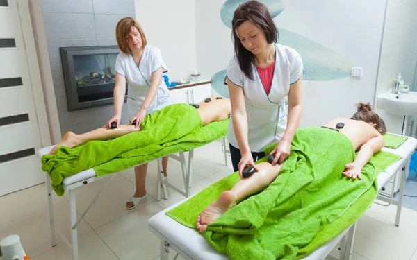 Masajista haciendo piernas masaje con piedras calientes —  Fotos de Stock