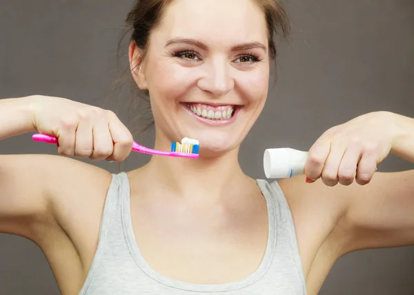 Donna che tiene lo spazzolino e ci mette sopra del dentifricio — Foto Stock