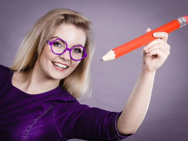 Mujer sonriente sostiene un lápiz grande en la mano — Foto de Stock