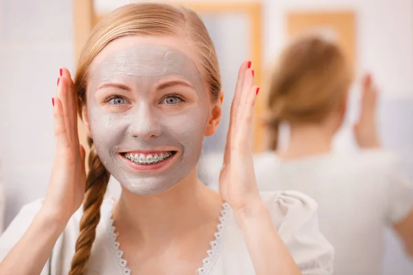 Mutlu genç kadın çamur maskesi yüzünde sahip — Stok fotoğraf