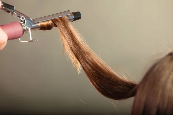 Estilista rizando el pelo para mujer joven. — Foto de Stock