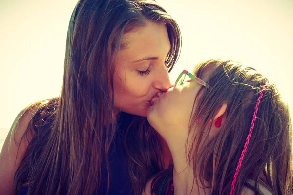 Woman and girl kissing near sea rocks — Stock Photo, Image